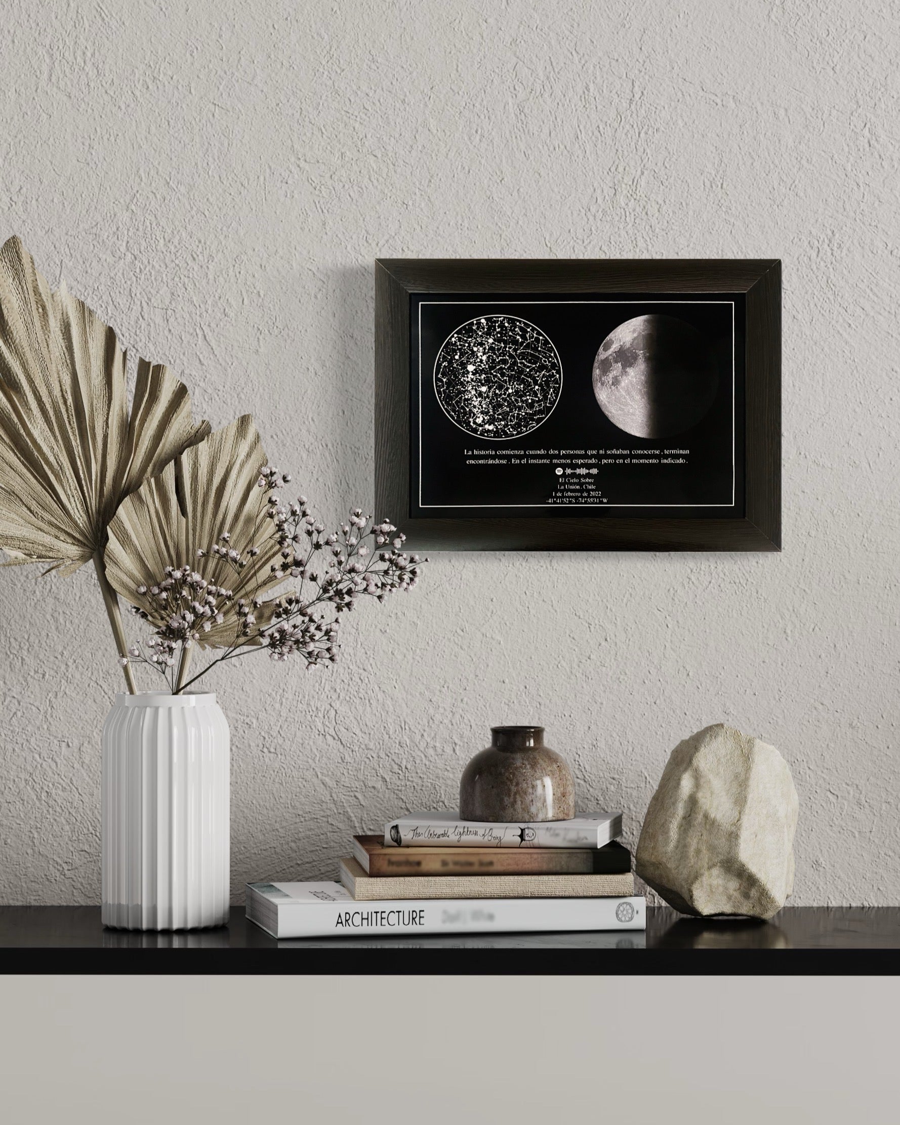 Mapa estelar con la fase lunar exacta de una fecha especial, enmarcado en negro sobre mesa decorativa de estilo moderno