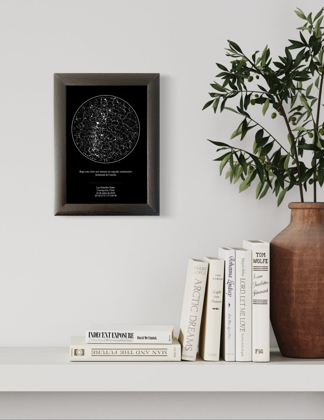 Mapa estelar tradicional personalizado en marco negro sobre repisa blanca con libros y jarrón decorativo, ideal como regalo de aniversario para parejas.