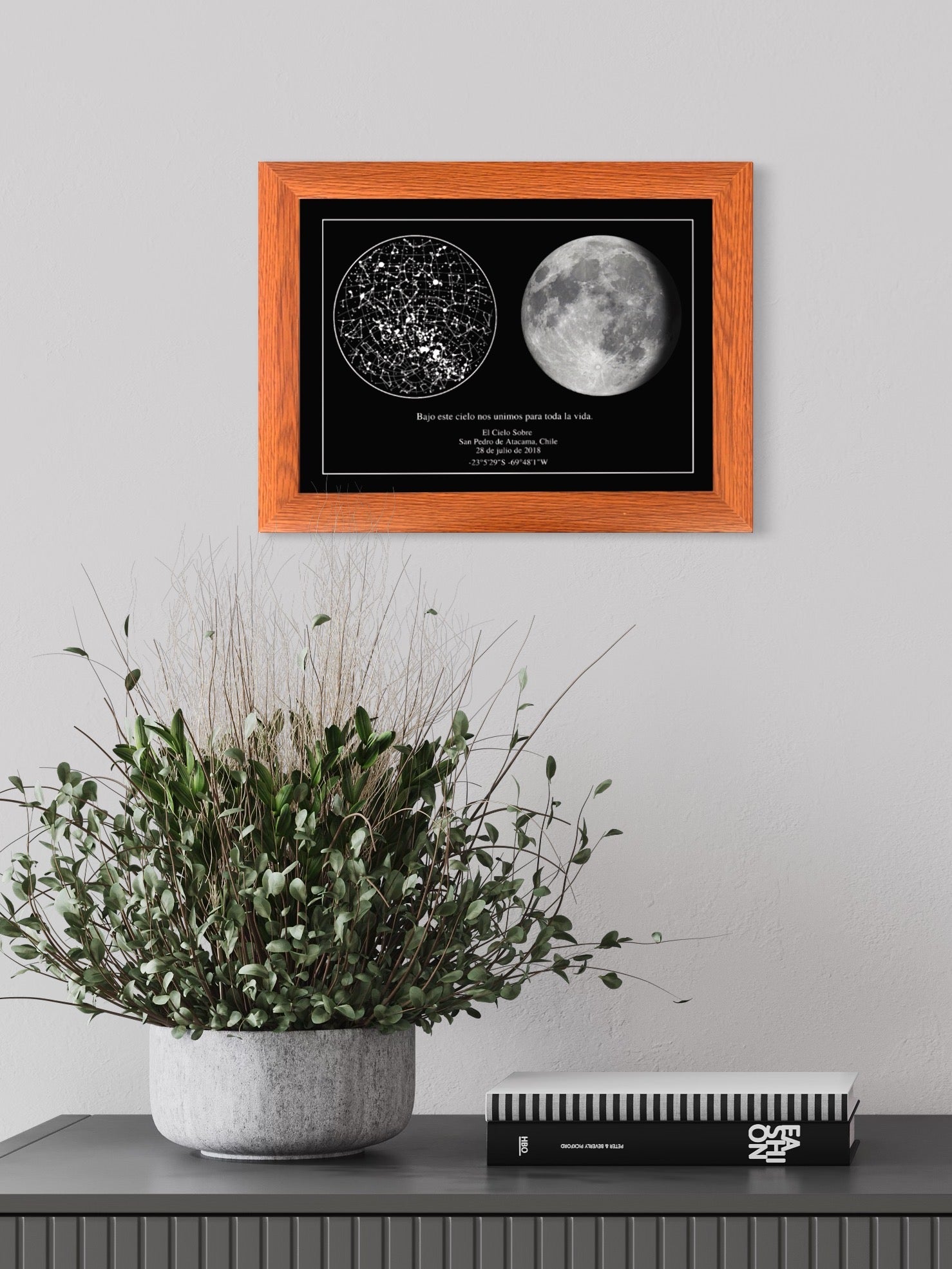 Cuadro de mapa estelar y fase de la luna enmarcado en café, colgado sobre mueble oscuro con jarrones decorativos