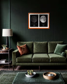 Mapa Estelar Modelo Doble en marco color madera colgado sobre un sofá verde oscuro en un living moderno, mostrando dos láminas: una del cielo estrellado y otra de la fase lunar.
