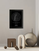 Mapa estelar tradicional en marco negro colgado sobre una repisa decorada con esculturas beige, jarrón y piñas, ideal como regalo de boda elegante.