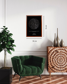 Mapa estelar XL enmarcado con medidas 36 x 51 cm sobre pared blanca junto a sillón verde y mueble de madera tallada