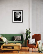 Mapa Lunar XXL colgado sobre sillón verde y sillón café en living moderno, mostrando la fase exacta de la luna de una fecha especial.