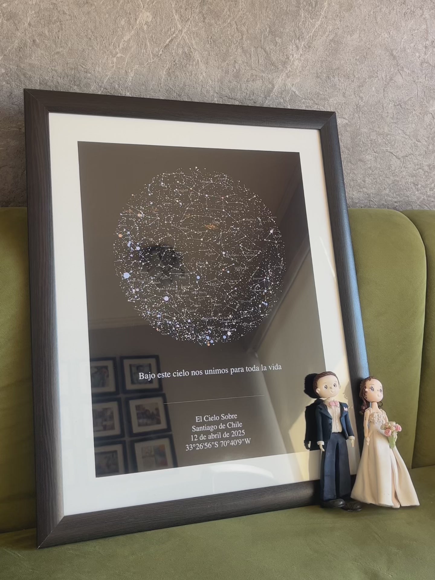 Mapa estelar XXL enmarcado apoyado sobre sofá verde con figuras de novios, regalo personalizado de boda