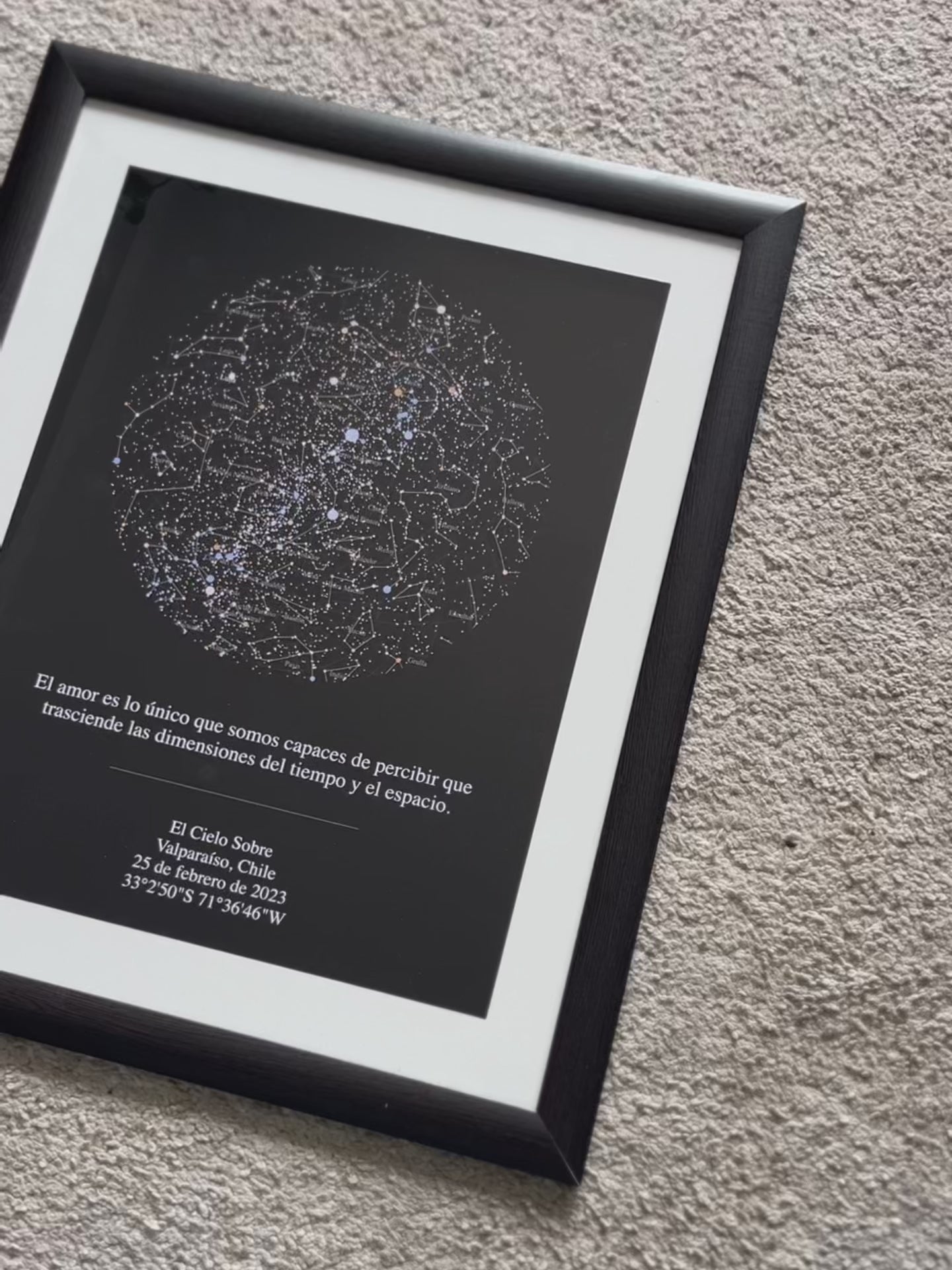 Mapa estelar XXL en marco negro con paspartú blanco apoyado sobre alfombra gris, regalo personalizado del cielo