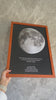 Mano sosteniendo cuadro Mapa Lunar XXL personalizado con fase exacta de la Luna, marco de madera y fondo gris, regalo romántico.