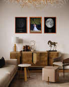Tres cuadros enmarcados con mapa estelar, foto de pareja y mapa lunar sobre pared blanca en sala de estar